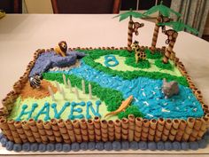 a birthday cake that is shaped to look like a river and jungle scene with animals on it