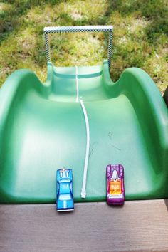 two toy cars sitting on top of a green slide