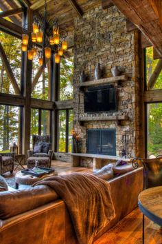 a living room with couches and a fireplace in the center surrounded by large windows