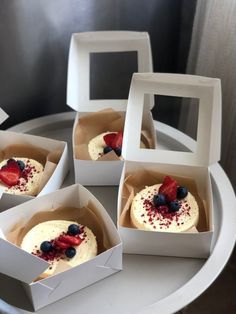 four small white boxes filled with desserts on top of a table