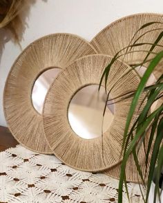 two round mirrors sitting on top of a table next to a potted plant