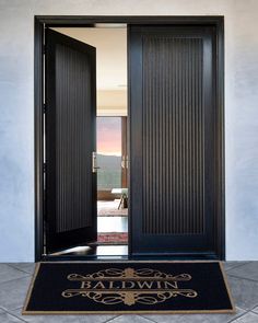 a black door with the words baldwin on it and an entrance mat in front of it