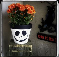 a potted plant with orange flowers in it and a skeleton decoration on the wall