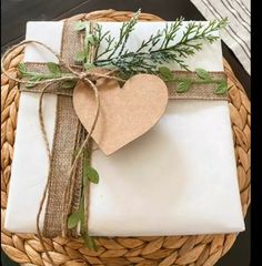 a gift wrapped in white paper and tied with twine on top of a wicker basket