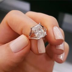 a woman's hand holding an engagement ring with a diamond on the top and bottom