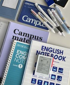 notebooks and pens are sitting on top of a table next to some other items