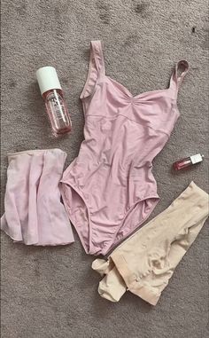 the contents of a pink swimsuit are laid out on the floor next to an empty bottle