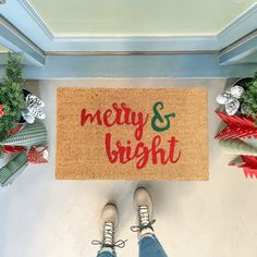 someone standing in front of a door mat that says merry and bright