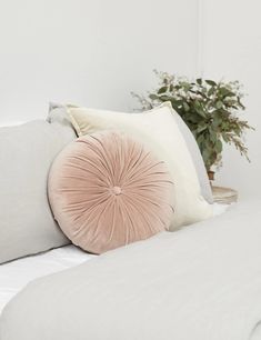 a white bed topped with pillows and a plant