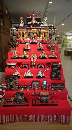 a red table topped with lots of figurines on top of wooden shelves next to each other