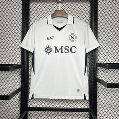 a white shirt hanging on a rack in front of a wall with black metal bars