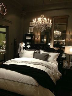 a bedroom with a chandelier hanging from the ceiling and two lamps on either side of the bed