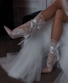 a woman in white high heeled shoes with lace overlays sitting on a chair