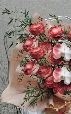 a bouquet of flowers sitting on top of a piece of paper with writing in the background