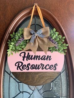 a wooden sign that says human resources hangs on the front door with a bow around it