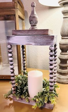 a candle sits on a wooden stand with greenery and candlesticks around it