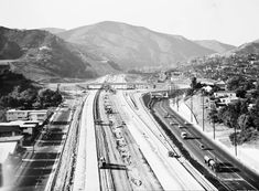 a black and white photo of train tracks in the middle of mountains with snow on them