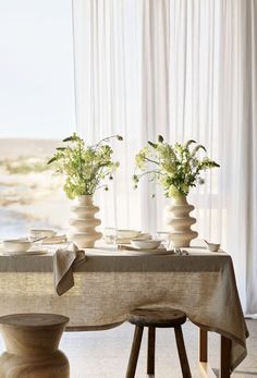 two vases filled with flowers sitting on top of a table next to a window