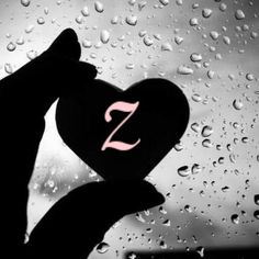 someone holding up a heart with the letter z on it in front of raindrops