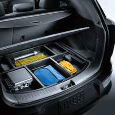 the trunk compartment of a car with cleaning supplies in it's tray and other items inside