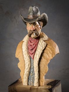 a busturine of a man wearing a cowboy hat and jacket on top of a wooden block