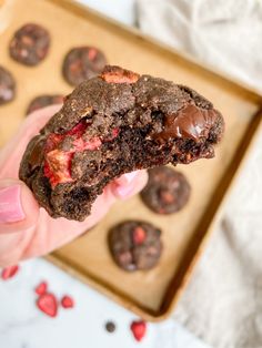 a person holding up a chocolate cookie in their hand