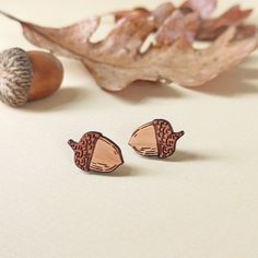 two small wooden earrings sitting on top of a table next to an acorn tree