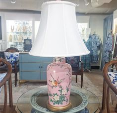 a pink vase sitting on top of a glass table next to a white lampshade