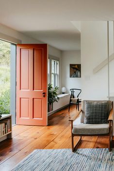 a living room filled with furniture and a red door in the middle of the room