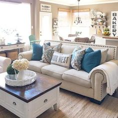 a living room filled with white furniture and lots of pillows on top of it's couches