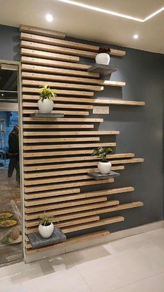 the wall is made out of wooden slats and has planters on each shelf