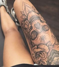 a woman's legs with tattoos and flowers on her leg, sitting on the floor