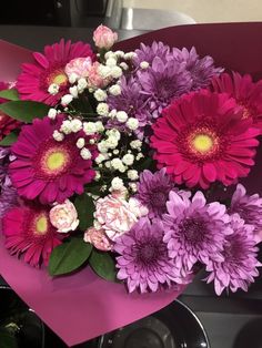 a bouquet of pink and purple flowers sitting on top of a table