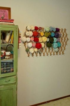 a green cabinet sitting next to a wall filled with lots of yarn on top of it