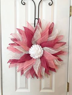 a pink and white wreath hanging on the front door