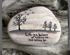 a painted rock with trees on it that says life is a balance of holding on and letting go