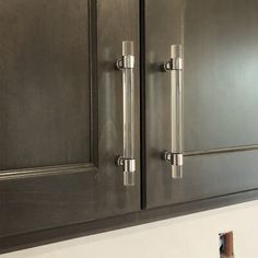 the kitchen cabinets are painted black and have silver handles on them, with a white wall in the background