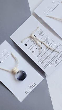 two pieces of paper with rope attached to them on top of white envelopes and papers