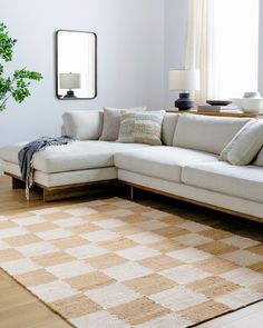 a white couch sitting on top of a wooden floor in a living room next to a window