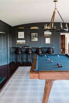 a pool table in the middle of a room with chairs and pictures on the wall