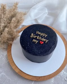 a birthday cake with the words happy birthday my on it next to some dry grass