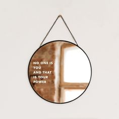 a round mirror hanging on a chain with the words, no one is you and that is your power