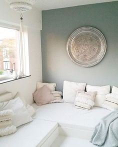 a white couch sitting in front of a window next to a round metal wall hanging