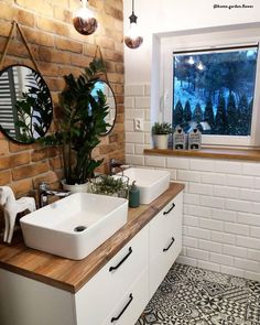 a bathroom with two sinks and a window in the wall above it is decorated with plants