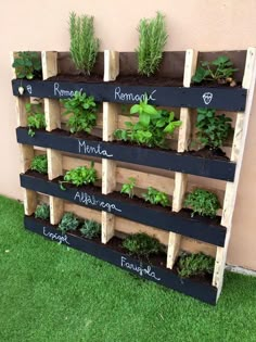 a wooden pallet filled with plants on top of green grass next to a building