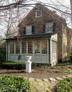 an old brick house with a white pedestal in the front yard and stone walkway leading up to it