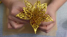 someone is holding a gold flower in their hands and it looks like they are making something out of paper