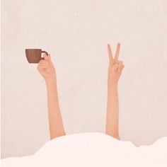 a person laying in bed with their hands up and holding a cup