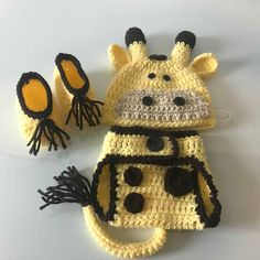 a crocheted cow hat, mittens and ear muffs