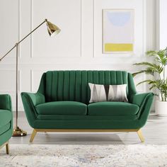 a living room with two green couches and a lamp on the side of the wall